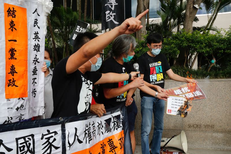 Pro-democracy protesters burn a sign during a demonstration near a flag raising ceremony for the anniversary of Hong Kong's handover to China in Hong Kong