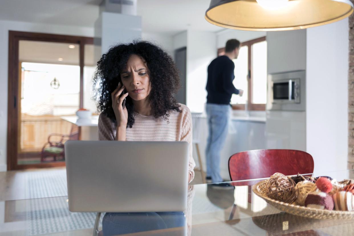 woman on phone looking at laptop