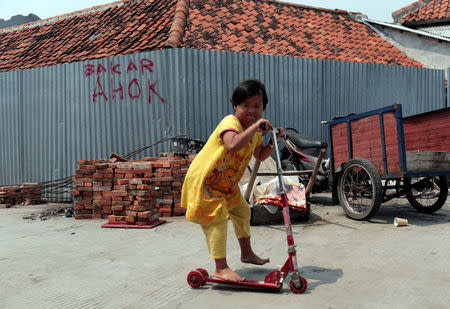 A child rides a scooter in Luar Batang area in Jakarta, Indonesia April 18, 2017. REUTERS/Beawiharta