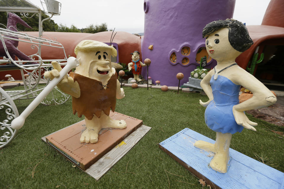 FILE -In this Monday, April 1, 2019, file photo, figurines of Barney and Betty Rubble stand outside the Flintstone House in Hillsborough, Calif. Technically, the owner of the fanciful Flintstones house in a posh San Francisco suburb settled a lawsuit with the town of Hillsborough. But the agreement will allow Fred and his friends to remain. (AP Photo/Eric Risberg, File)