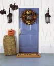 <p>Even the DIY-phobic can make their porches a little more festive for trick-or-treaters by swapping in a new doormat and adding a <a href="https://www.countryliving.com/diy-crafts/g1988/fall-craft-projects/" rel="nofollow noopener" target="_blank" data-ylk="slk:fall wreath;elm:context_link;itc:0;sec:content-canvas" class="link ">fall wreath</a>, a bale of hay, and some faux hanging bats. </p>