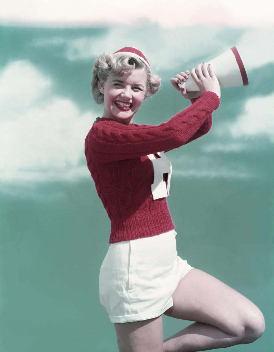 A cheerleader wearing a knit sweater and white skirt in the 1950s.