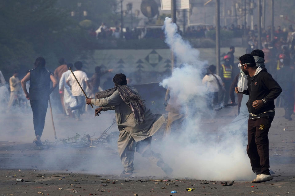 A supporter of former Prime Minister Imran Khan hurls back a tear gas shell fired by riot police officers to disperse them during clashes, in Lahore, Pakistan, Wednesday, March 15, 2023. Clashes between Pakistan's police and supporters of Khan continued outside his home in the eastern city of Lahore on Wednesday, a day after officers went to arrest him for failing to appear in court on graft charges. (AP Photo/K.M. Chaudary)