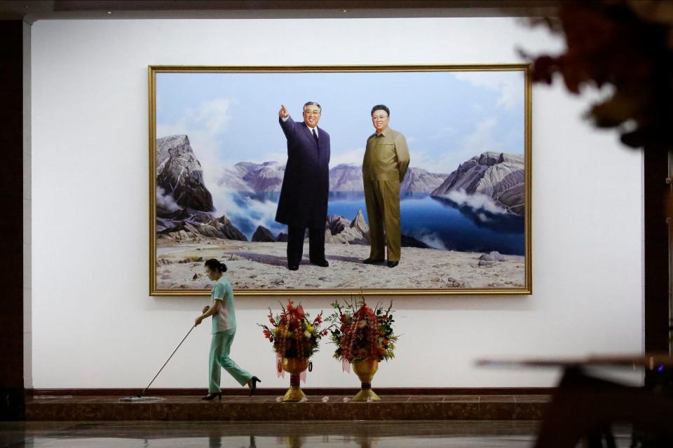 A staff member sweeps the floor in a hotel lobby in front of a picture featuring portraits of the late North Korean leaders Kim Il Sung, left, and Kim Jong Il on June 19, 2017, in Pyongyang, North Korea.