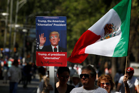 A man holds up a placard with an image of U.S. President Donald Trump during a march to protest against Trump's proposed border wall and to call for unity, in Mexico City, Mexico, February 12, 2017. REUTERS/Jose Luis Gonzalez