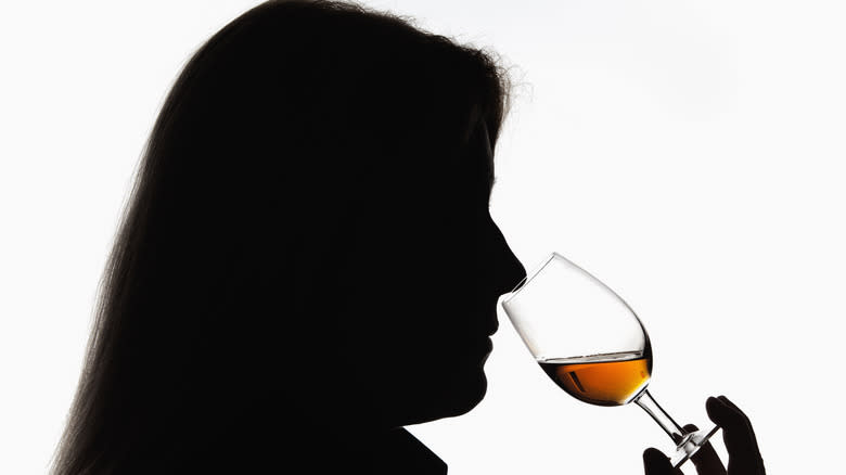 silhouette of woman sniffing whiskey