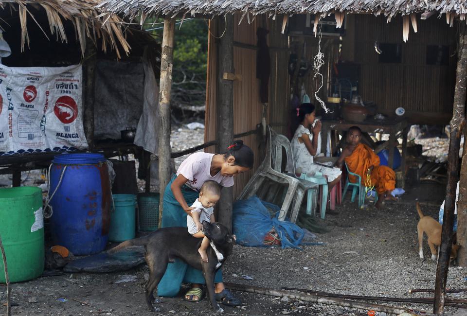 In this Feb. 11, 2014 photo, a Myanmarese woman lets a child ride a stray dog in Ma Kyone Galet village, inhabited by Moken and Myanmarese fishermen, on Bocho Island in Mergui Archipelago, Myanmar. The Moken, the sea nomads who have inhabited the Mergui archipelago for centuries, would make ideal nature guides. (AP Photo/Altaf Qadri)