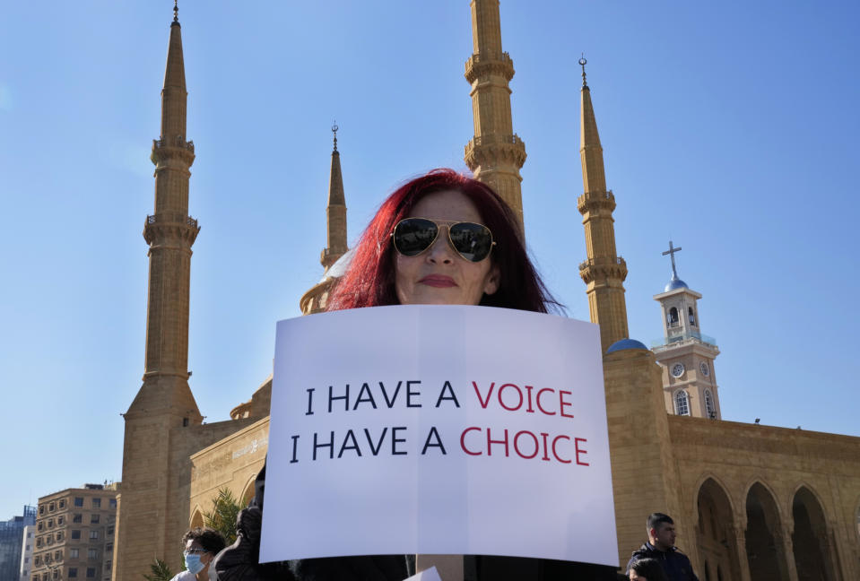 A protester holds a placard during a rally to protest measures imposed against people who are not vaccinated, in Beirut, Lebanon, Saturday, Jan. 8, 2022. Vaccinations are not compulsory in Lebanon but in recent days authorities have become more strict in dealing with people who are not inoculated or don't carry a negative PCR test. (AP Photo/Hussein Malla)