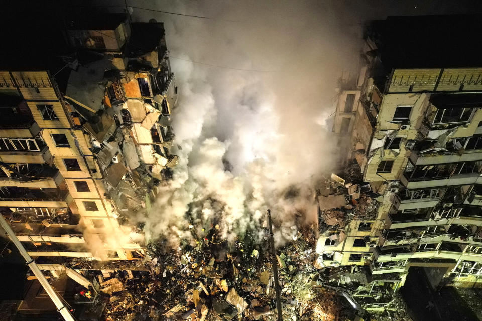 Emergency workers clear the rubble after a Russian rocket hit a multistory building leaving many people under debris in the southeastern city of Dnipro, Ukraine, on Jan. 14, 2023.  (Evgeniy Maloletka / AP)