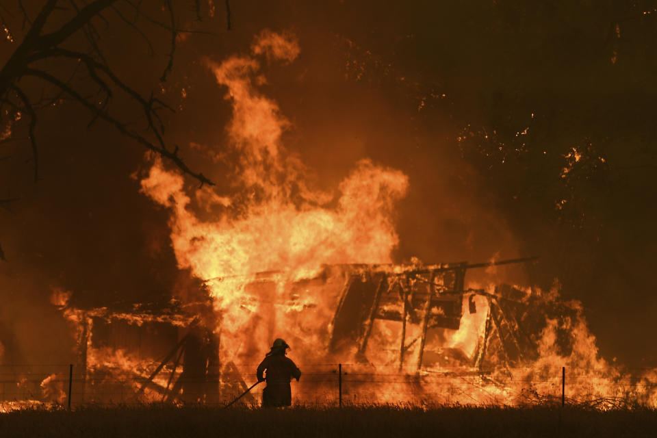 In this Saturday, Dec. 21 ,2019, photo, NSW Rural Fire Service crews fight the Gospers Mountain Fire as it impacts a structure at Bilpin. Australian Prime Minister Scott Morrison on Sunday, Dec. 22, apologized for taking a family vacation in Hawaii as deadly bushfires raged across several states, destroying homes and claiming the lives of two volunteer firefighters.(Dan Himbrechts/AAP Images via AP)