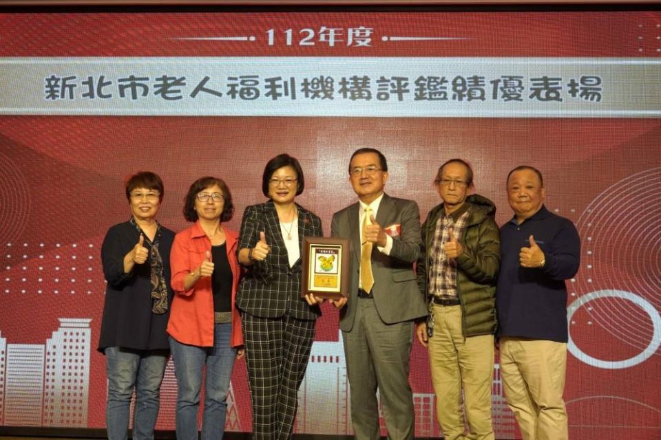 《圖說》私立育昇老人長期照顧中心主任張吉雄（右3）從社會局長李美珍（左3）手中接過評鑑優等獎牌。〈社會局提供〉