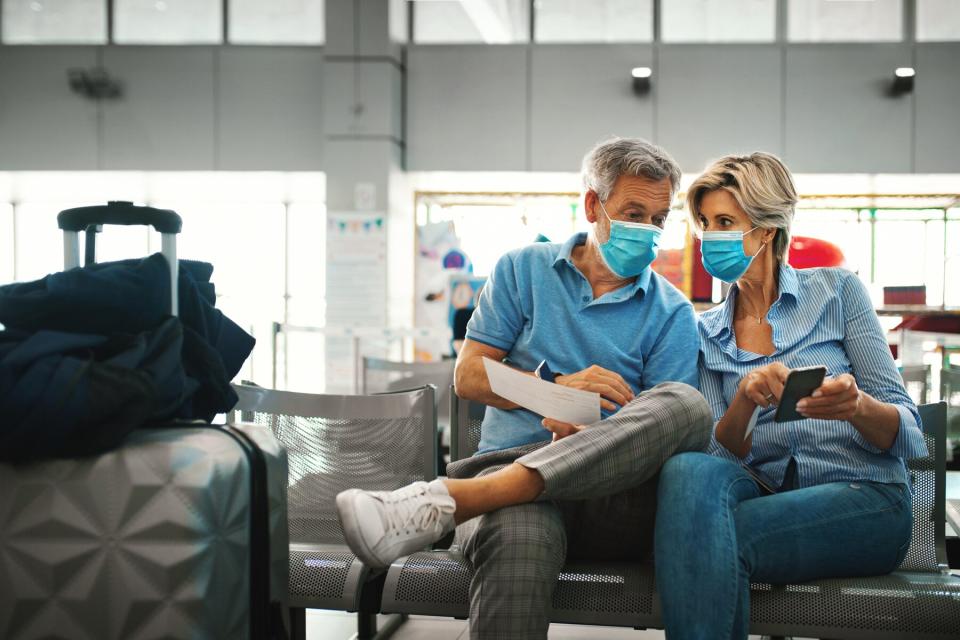 Closeup front view of a mid 50's couple waiting for a flight after coronavirus travel ban has been lifted.