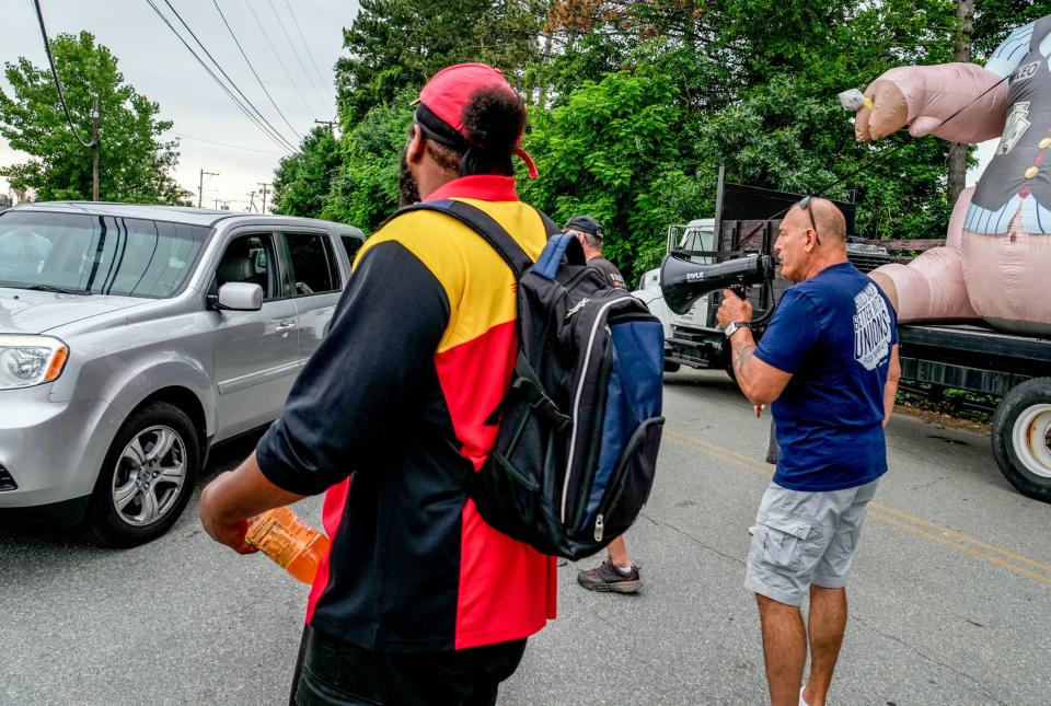 DHL workers and union supporters confront a driver entering the property with calls of "scab."