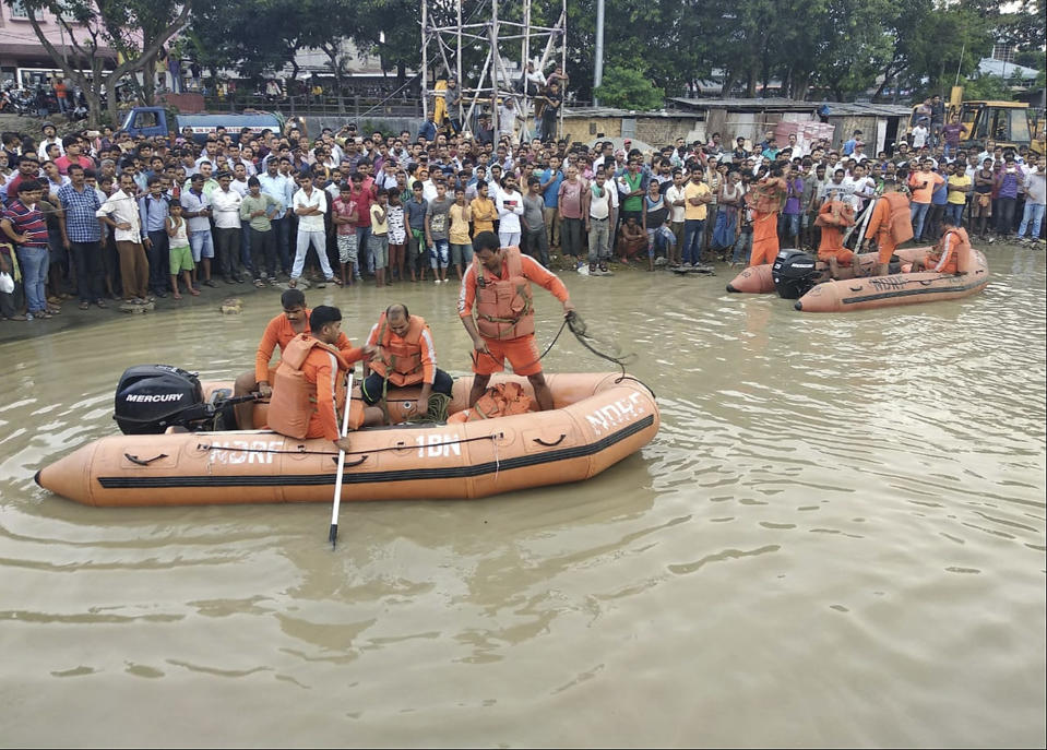 People watch rescuers search the waters of the Brahmaputra River