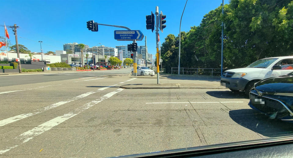 A photo of drivers stopping a meter or more behind a red traffic light.