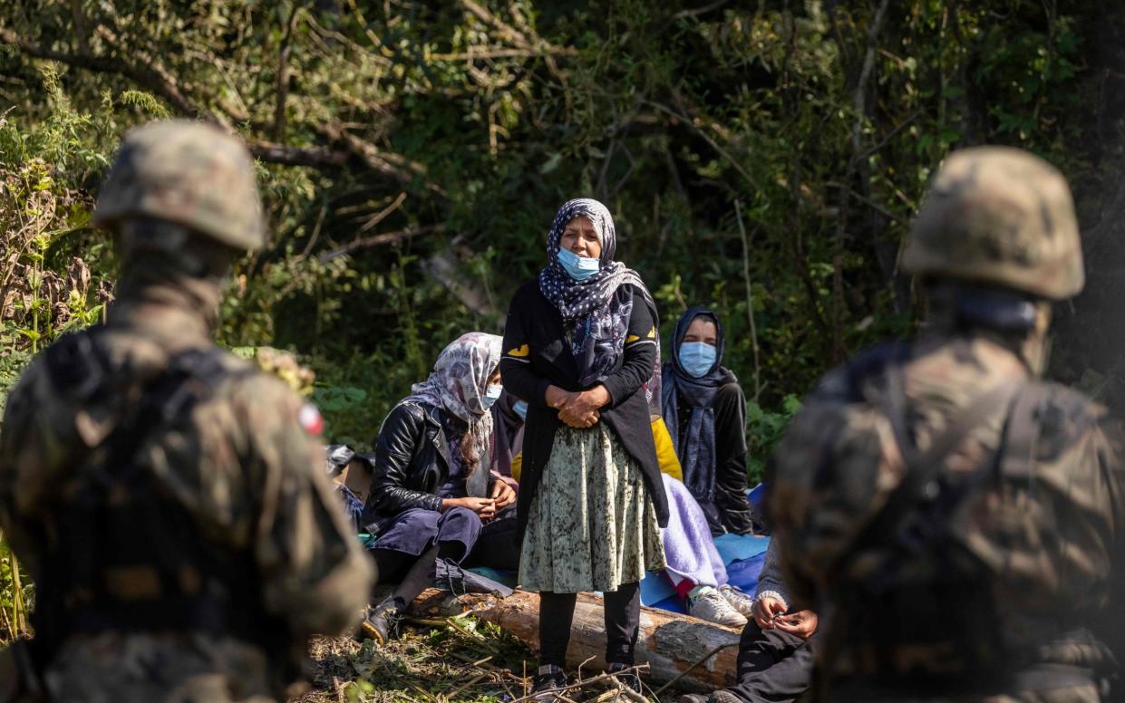 Polish border guards across from migrants believed to be from Afghanistan in a village close to the border with Belarus - WOJTEK RADWANSKI /AFP