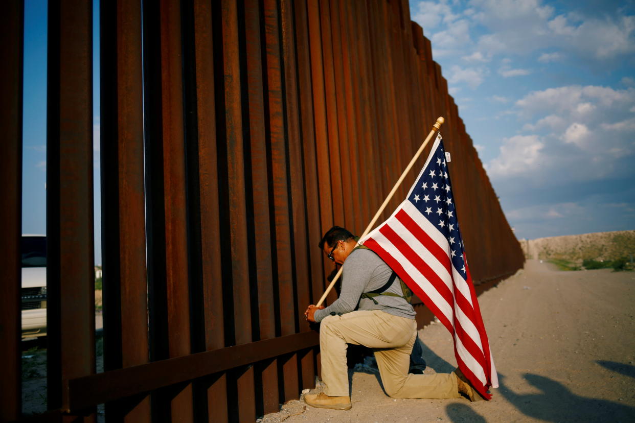 A U.S. Marine veteran prays near the border wall between the U.S. and Mexico in Sunland Park, New Mexico, July 21, 2021. REUTERS/Jose Luis Gonzalez