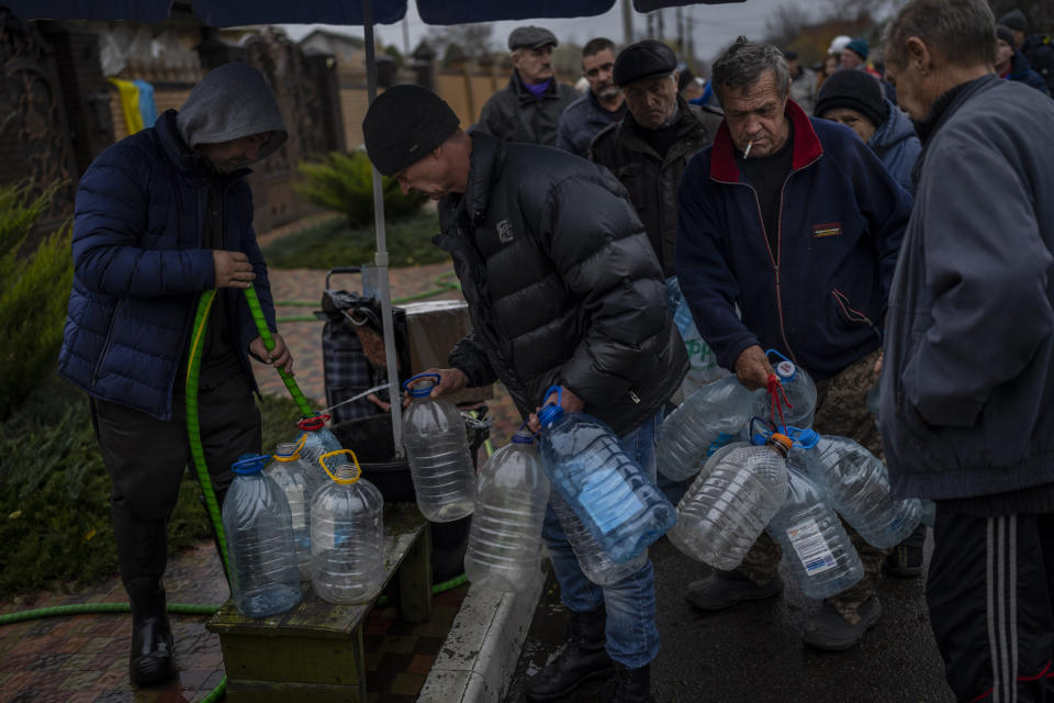 Residents fill containers with drinking water in Kherson, southern Ukraine, Sunday, Nov. 20, 2022. Russian forces fired tank shells, rockets and other artillery on the city of Kherson, which was recently liberated from Ukrainian forces. (AP Photo/Bernat Armangue)