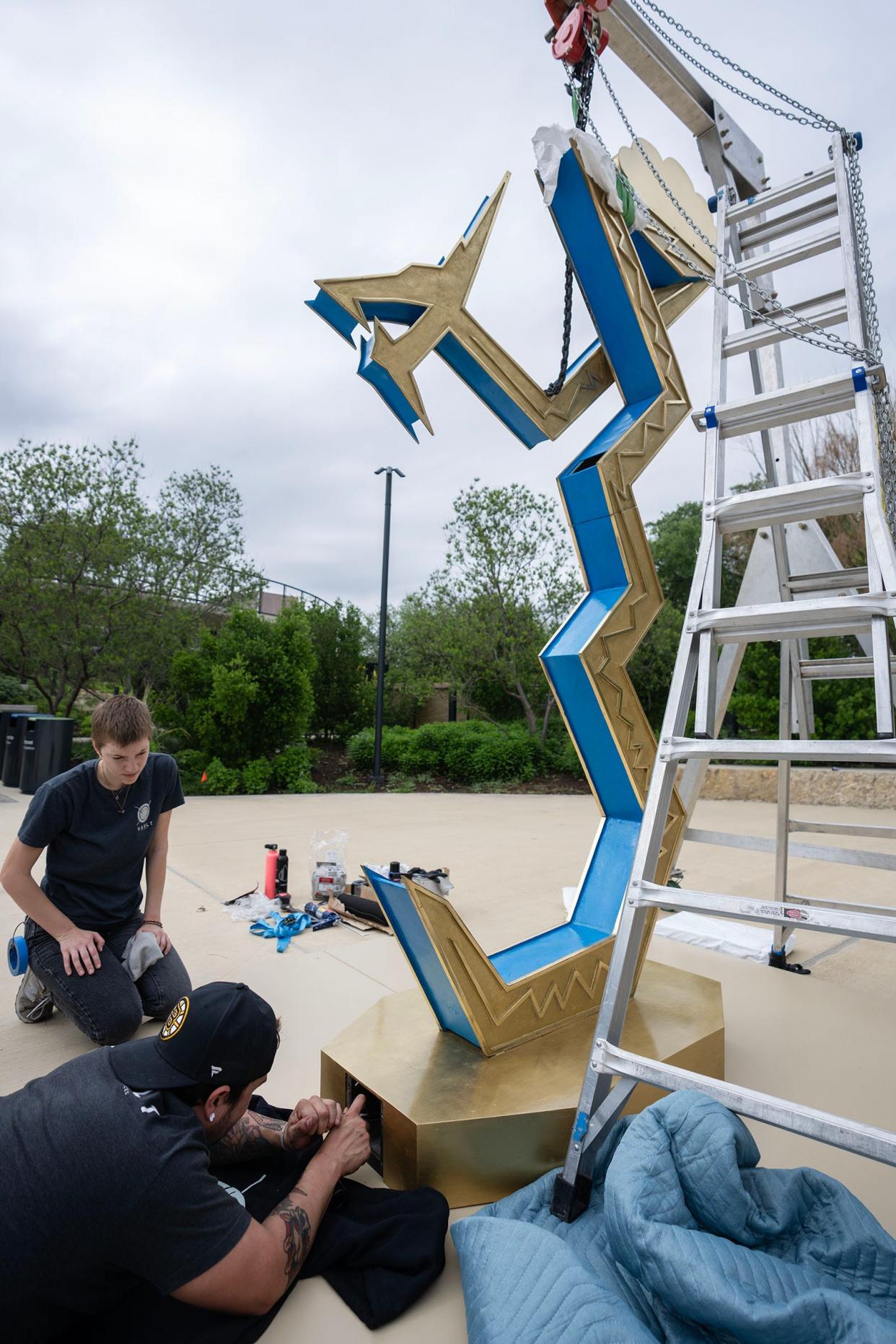 Visual Fine Arts Services employees Chris Dennis and Abi Waller help install artist Guadalupe Maravilla's art installation, "Serpent of the Sun and the Moon," at Waterloo Park.