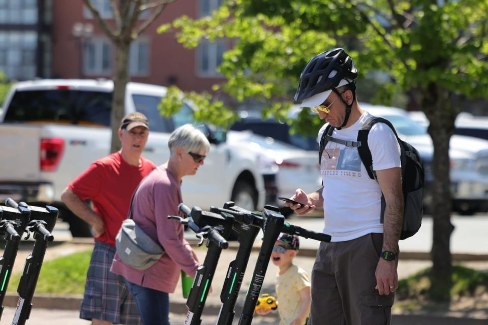 A e-scooter user signs out a HFX eScooter via the mobile app on his phone on the Halifax waterfront.