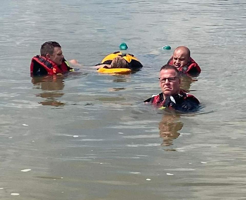 The Fort Smith Fire Department rescue team, on left, driver Brian Evans, Capt. Jesse Chandler, and Battalion Chief Ethan Millard, front with eyeglasses, rescue a man who jumped from the Garrison Bridge into the Arkansas River in Fort Smith on July 2, 2022.