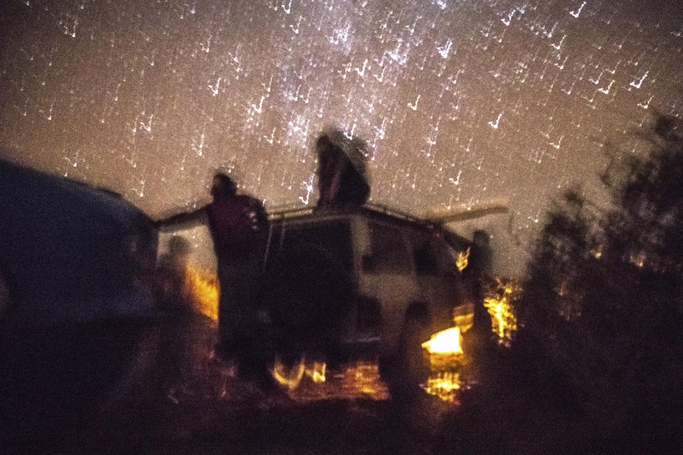 Smugglers pause atop a vehicle as they attempt to lift a fishing boat in a remote desert out of the town of Dakhla in Morocco-administered Western Sahara, Tuesday, Dec. 22, 2020. Beneath a star-packed sky in the Sahara, smugglers and handymen unearth a boat buried in the sand, a made-to-order vessel for carrying migrants from the North African coast to Spain's Canary Islands. (AP Photo/Mosa'ab Elshamy)