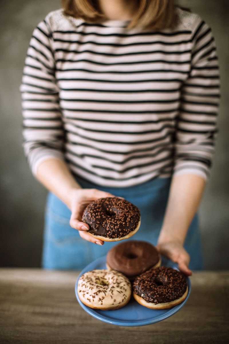 A woman presents a plate of donuts