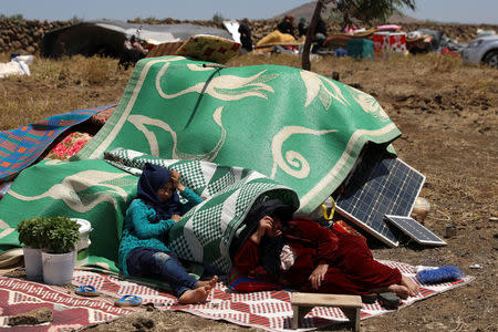 Internally displaced people from Deraa province sit with their belongings near the Israeli-occupied Golan Heights in Quneitra, Syria June 29, 2018. REUTERS/Alaa Al-Faqir