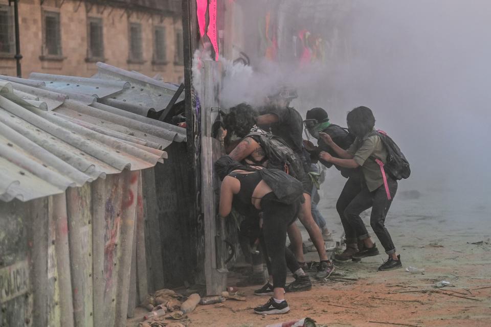 Women clash with the police, behind a fence in front of the National Palace, as they protest during a demonstration to commemorate the International Women's Day  in Mexico City, on March 8, 2021. (Photo by PEDRO PARDO / AFP) (Photo by PEDRO PARDO/AFP via Getty Images)