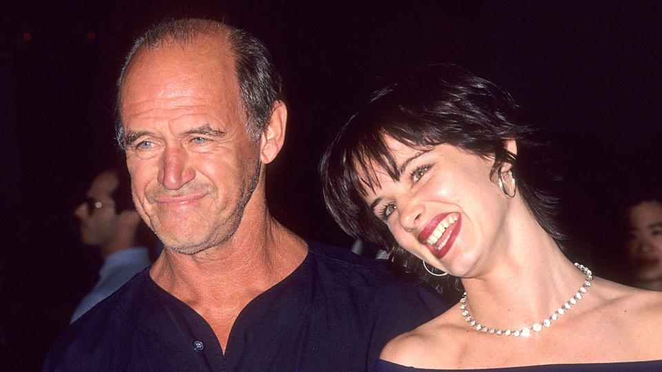 Juliette and Geoffrey smiling together at a red carpet event. They are both wearing navy. 