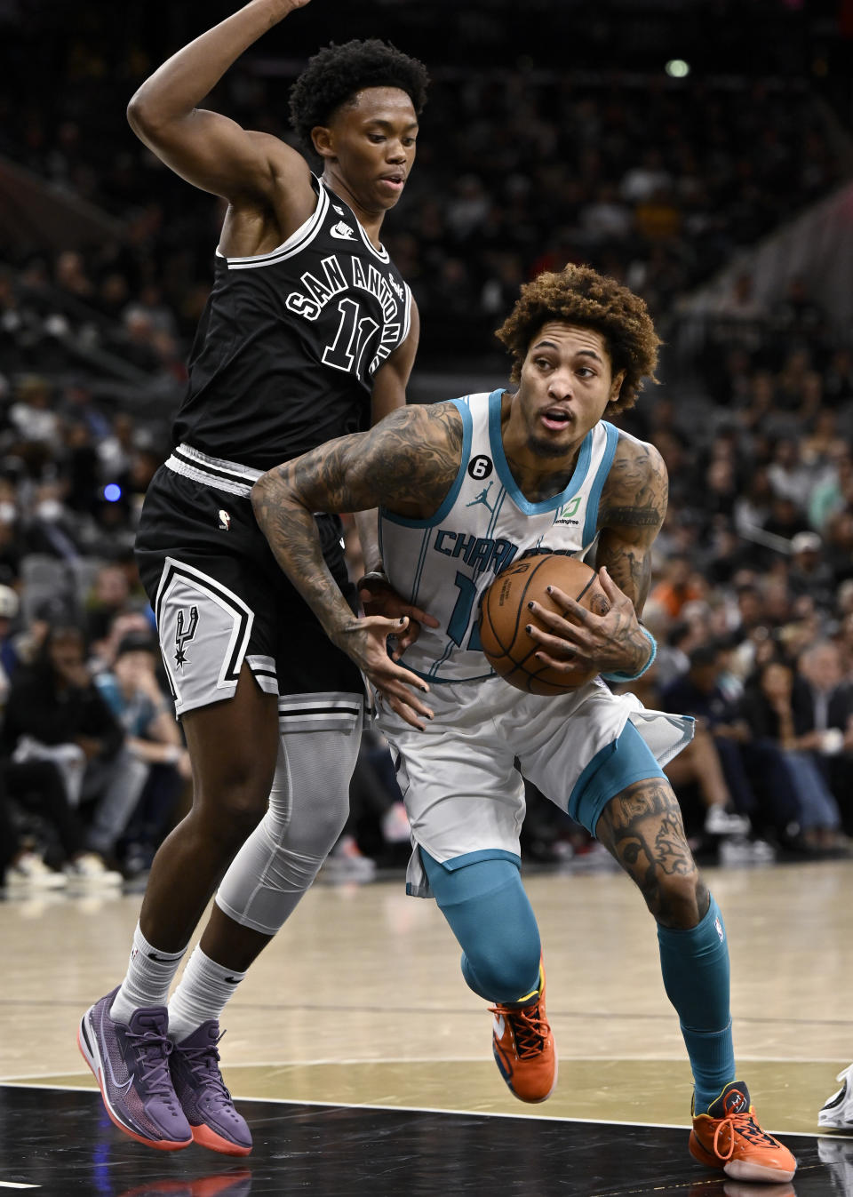 Charlotte Hornets' Kelly Oubre Jr., right, drives against San Antonio Spurs' Josh Primo during the first half of an NBA basketball game Wednesday, Oct. 19, 2022, in San Antonio. (AP Photo/Darren Abate)