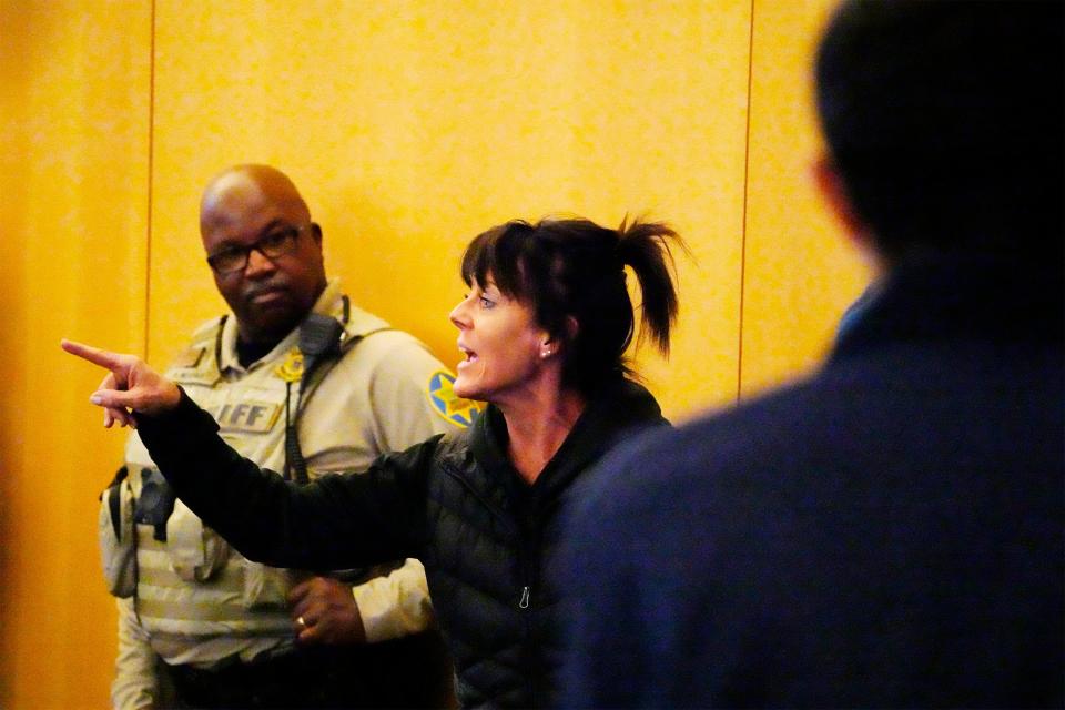 A woman leaves the room after not following decorum at the Maricopa County Board of Supervisors general election canvass special meeting on Nov. 28, 2022, in Phoenix.