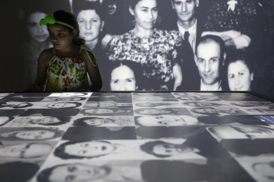 A youth looks at photos on an interactive table displaying the photos and stories of the thousands of people who took refuge in Brazil during the Holocaust at the Holocaust Victims Memorial on the first day it opened to the public in Rio de Janeiro, Brazil, Thursday, Jan. 19, 2023. (AP Photo/Bruna Prado)