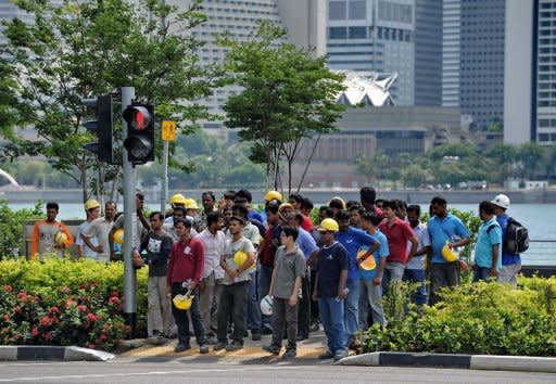 Construction workers wait to cross a street in Singapore on June 10, 2011. Maligned by some Singaporeans for supposedly stealing jobs and causing overcrowding, foreigners holding work permits numbered more than 870,000 at the end of 2010 out of Singapore's total population of 5.1 million