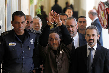 FILE PHOTO: An Israeli prison guard escorts jailed Fatah leader Marwan Barghouti (C) to a deliberation at Jerusalem Magistrate's court January 25, 2012. REUTERS/Baz Ratner/File Photo