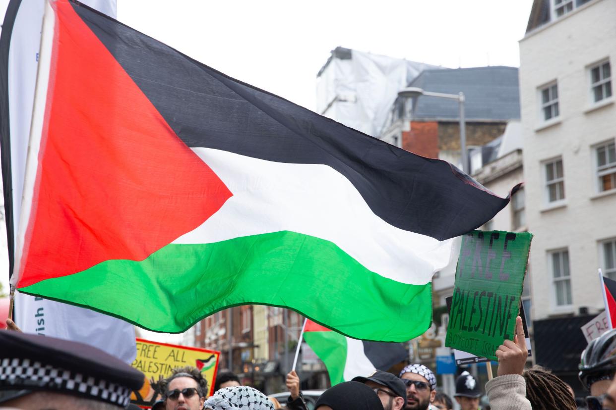 Pro-Palestinian protesters gather with flags and placards during a protest outside the gates to the Embassy of Israel in London.