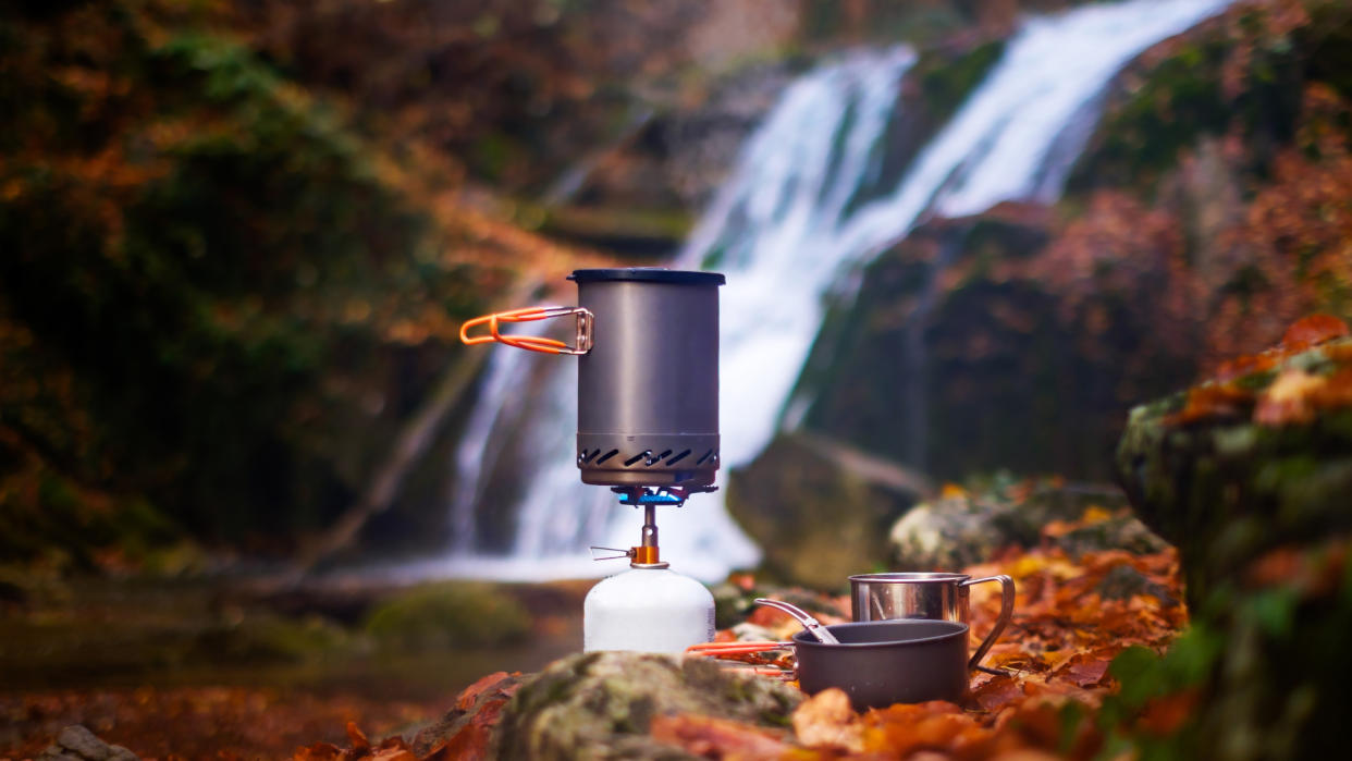  A camping stove with a waterfall behind it. 