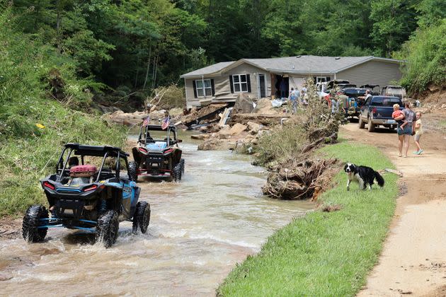 ATV drivers ferrying generator fuel and water drive around Jessica Willett's home, which was torn from its foundations during flooding and left in the middle of the road, along Bowling Creek, on July 31. (Photo: Chris Kenning/USA Today Network/REUTERS)