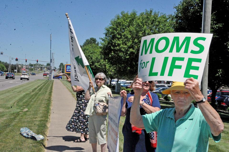 Bernadette Rieman holds up a "Moms for life" sign at a pro-life rally along Burbank Road in Wooster.