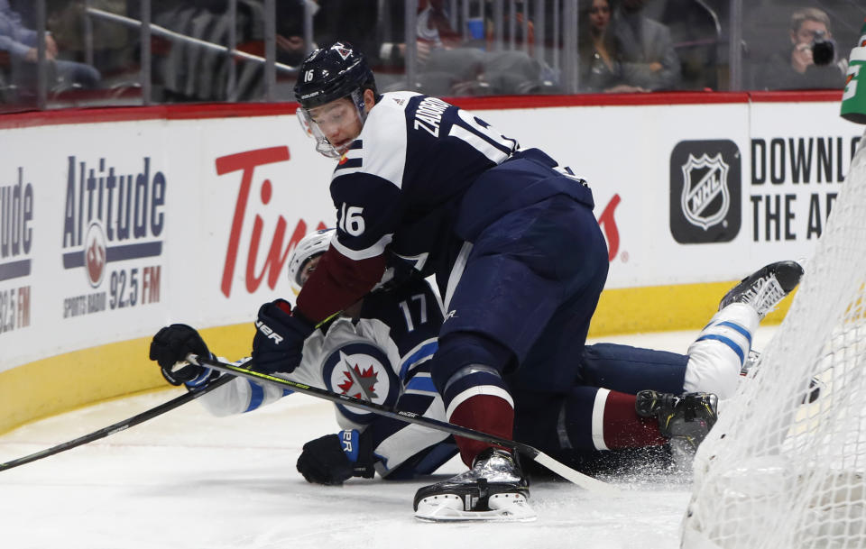 Colorado Avalanche defenseman Nikita Zadorov, front, knocks down Winnipeg Jets center Adam Lowry as he tries to control the puck during the second period of an NHL hockey game Tuesday, Dec. 31, 2019, in Denver. (AP Photo/David Zalubowski)