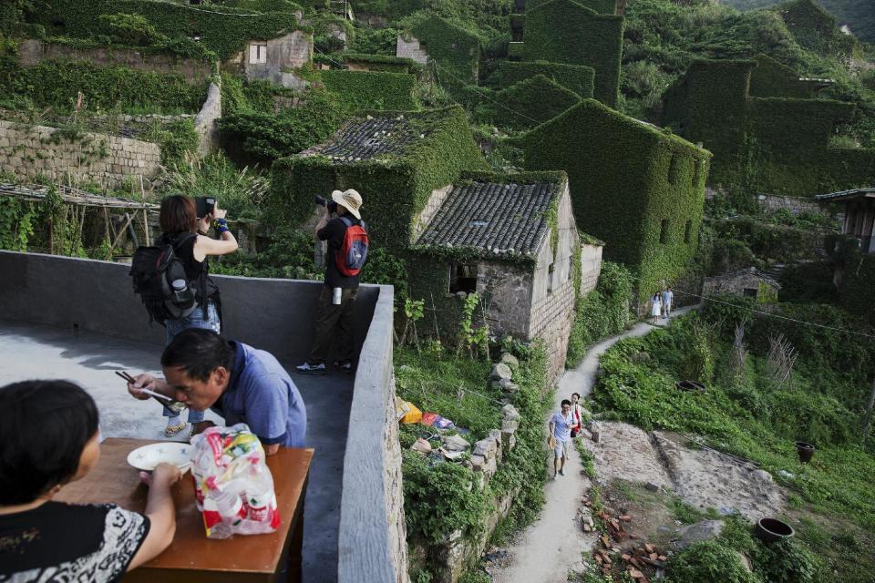 Tourists visit the abandoned fishing village of Houtouwan on the island of Shengshan as its former residents, now visiting, have lunch July 25, 2015. (REUTERS/Damir Sagolj)