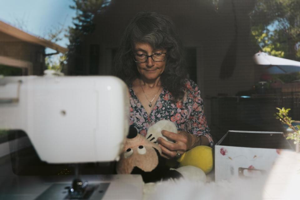 A woman adds fresh stuffing to a vintage Mickey Mouse toy.