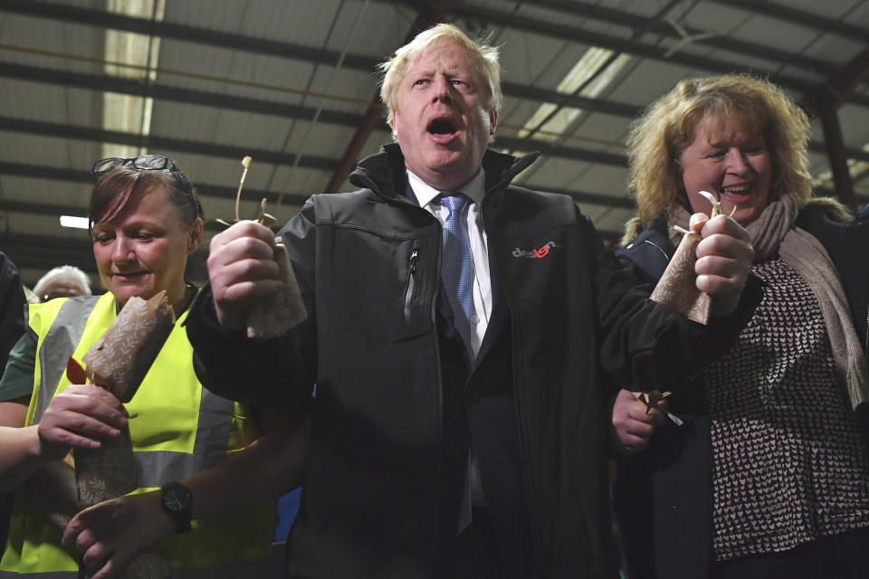 Britain's Prime Minister Boris Johnson, centre, gestures after pulling crackers with staff members during a visit to IG Design Group, wrapping paper designer and producer in Hengoed, south Wales, Wednesday, Dec. 11, 2019 on the final day of campaigning for the general election. Britain goes to the polls on Dec. 12. (Ben Stansall/Pool Photo via AP)