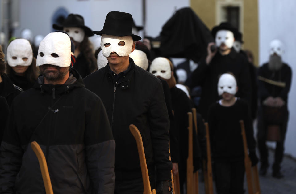 Participants dressed in black, wearing masks, beating drums and pushing small carts that make a synchronized and loud sound take part in an Easter procession through the streets of Ceske Budejovice, Czech Republic, Friday, April 19, 2019. (AP Photo/Petr David Josek)