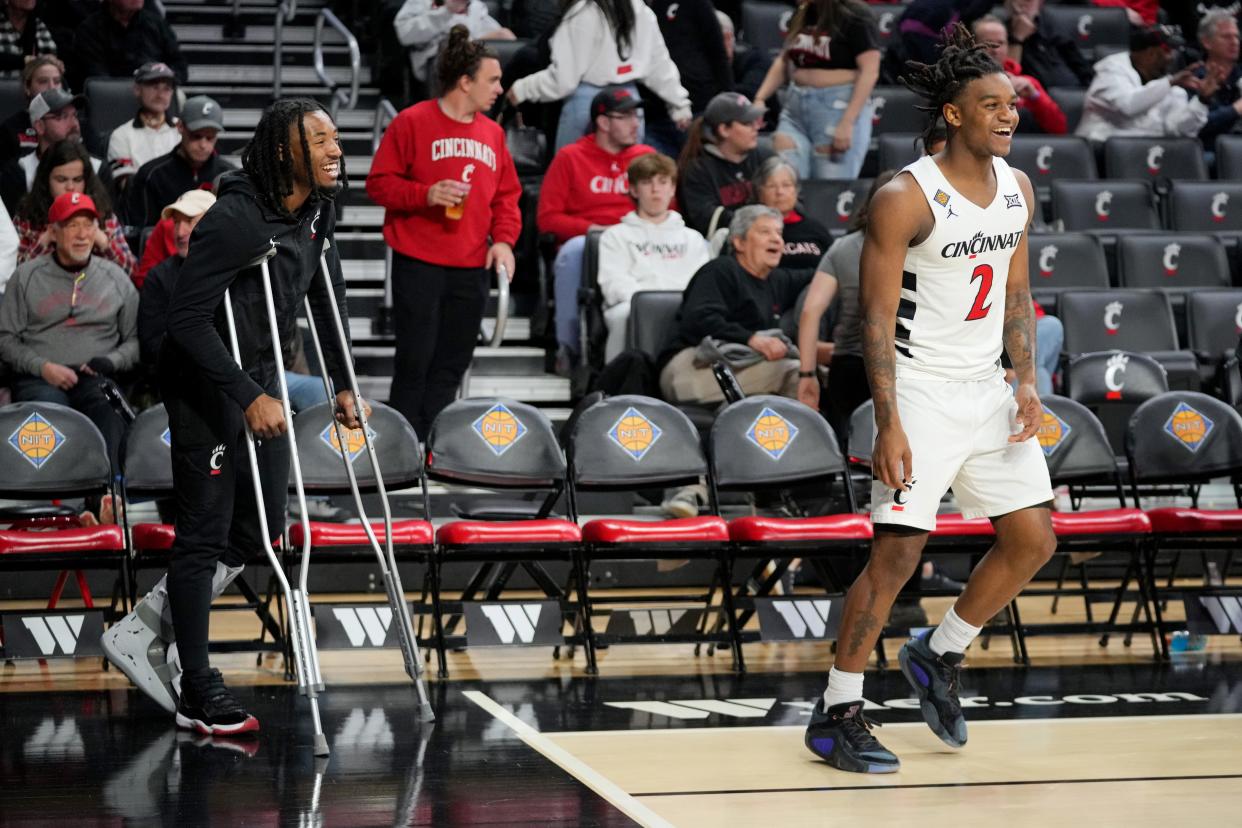 Cincinnati Bearcats guard Day Day Thomas (1), who suffered an injury in the previous game, shares a laugh with Cincinnati Bearcats guard Jizzle James (2) during halftime of a college basketball game against the Bradley Braves in a second-round game of the National Invitation Tournament,, Saturday, March 23, 2024, at Fifth Third Arena in Cincinnati.