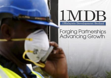 A construction worker talks on the phone in front of a 1Malaysia Development Berhad (1MDB) billboard at the Tun Razak Exchange development in Kuala Lumpur, Malaysia, in this February 3, 2016 file photo. REUTERS/Olivia Harris/Files