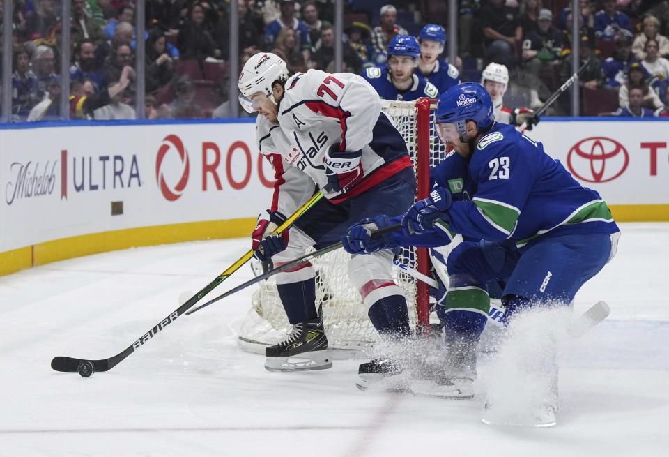 Washington Capitals' T.J. Oshie (77) is checked by Vancouver Canucks' Elias Lindholm (23) during the second period of an NHL hockey game in Vancouver, British Columbia, Saturday, March 16, 2024. (Darryl Dyck/The Canadian Press via AP)