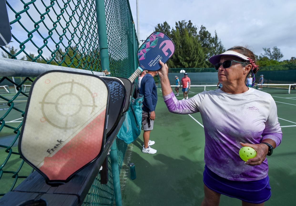 Debbie Sandh, of Fort Pierce, picks out her pickleball paddle from a rack alongside the courts for her turn to play at Pepper Park Beachside Park, 3302 N. State Road A1A on north Hutchinson Island on Saturday, Jan. 27, 2023, in St. Lucie County. Players place their paddle in the rack as a marker of rotation for their next game, when the courts are full. "We're really looking forward to the new courts the county promised us last year," Sandh said. "Lots of people here every day, and we love it."