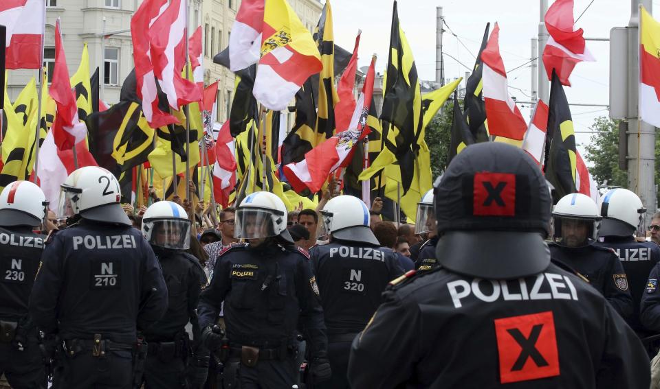 FILE - In this June 11, 2016 file photo police forces stand in front of demonstrators during a rally of the group Austrian protesters against migrants in Vienna, Austria. Austria was among the first countries in Europe to put out the welcome mat to migrants when the first waves of people fleeing war and poverty reached the continent. Now, its focus is showing them the door. Parliament is set to pass a law stripping denied asylum-seekers of pocket money, food and shelter, potentially leaving them on the street. (AP Photo/Ronald Zak, file)