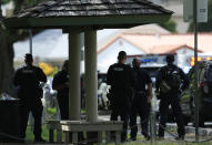 Honolulu police prepare to take defensive positions with their weapons after a shooting and domestic incident at a residence on Hibiscus Road near Diamond Head on Sunday, Jan. 19, 2020, in Honolulu. Witnesses say at least two Honolulu police officers were shot and two civilians were injured. Moments after the shooting, the house was set on fire, possibly by the suspect. (Jamm Aquino/Honolulu Star-Advertiser via AP)